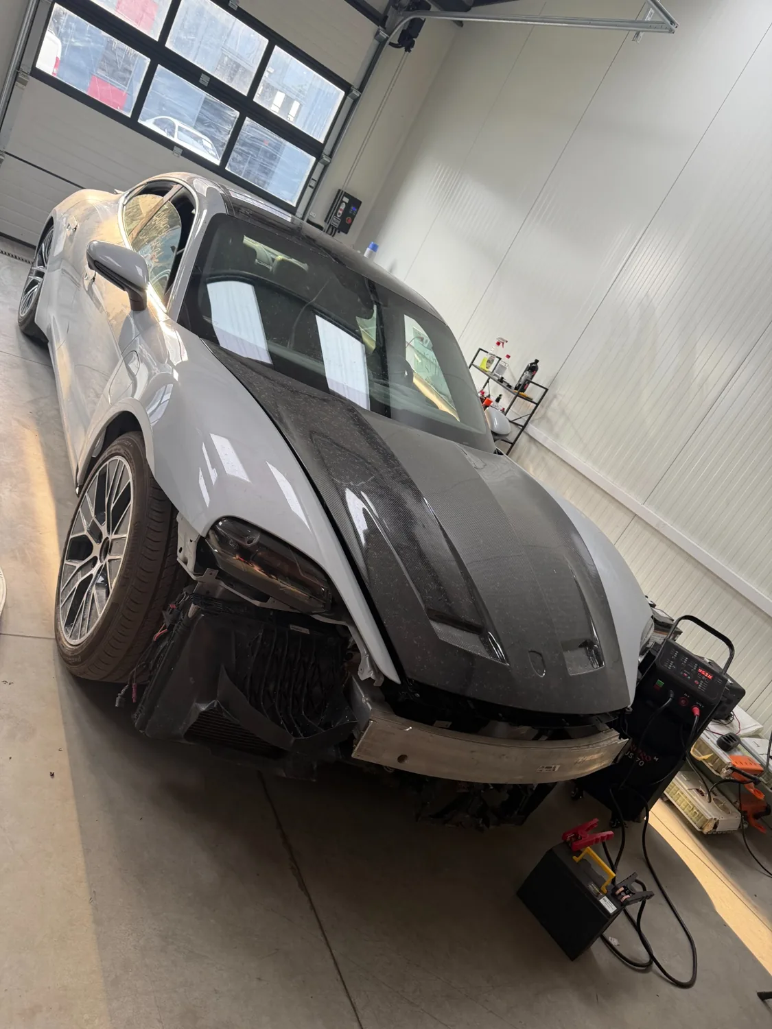 Porsche Taycan в мастерской: передняя часть разобрана для доступа к компонентам.